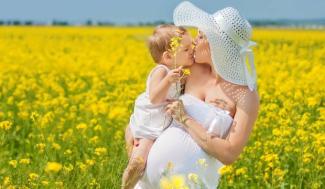 Sarı çiçeklerle dolu bir tarlada, beyaz elbise giymiş hamile bir kadın ve kucağında küçük bir çocuk. Kadın geniş kenarlı beyaz bir şapka takıyor. Çocuk ve kadın birbirlerine sarılmış ve öpüşüyorlar. Çocuk elinde sarı çiçekler tutuyor. Arka planda uçsuz bucaksız sarı çiçek tarlası ve mavi gökyüzü görünüyor. Görüntüde sıcak, neşeli ve sevgi dolu bir atmosfer var.