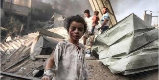 Savaş sonrası yıkıntılar arasında bir kız çocuğu. Ön planda küçük bir kız çocuğunun üstü başı kirli ve yırtık, yüzünde kanlı yaralar var. Arkada enkaz haline gelmiş binalar ve duman yükseliyor. Birkaç yetişkin ve bir çocuk daha arka planda yıkıntıların arasında duruyor. Ortamda korku ve çaresizlik hâkim.